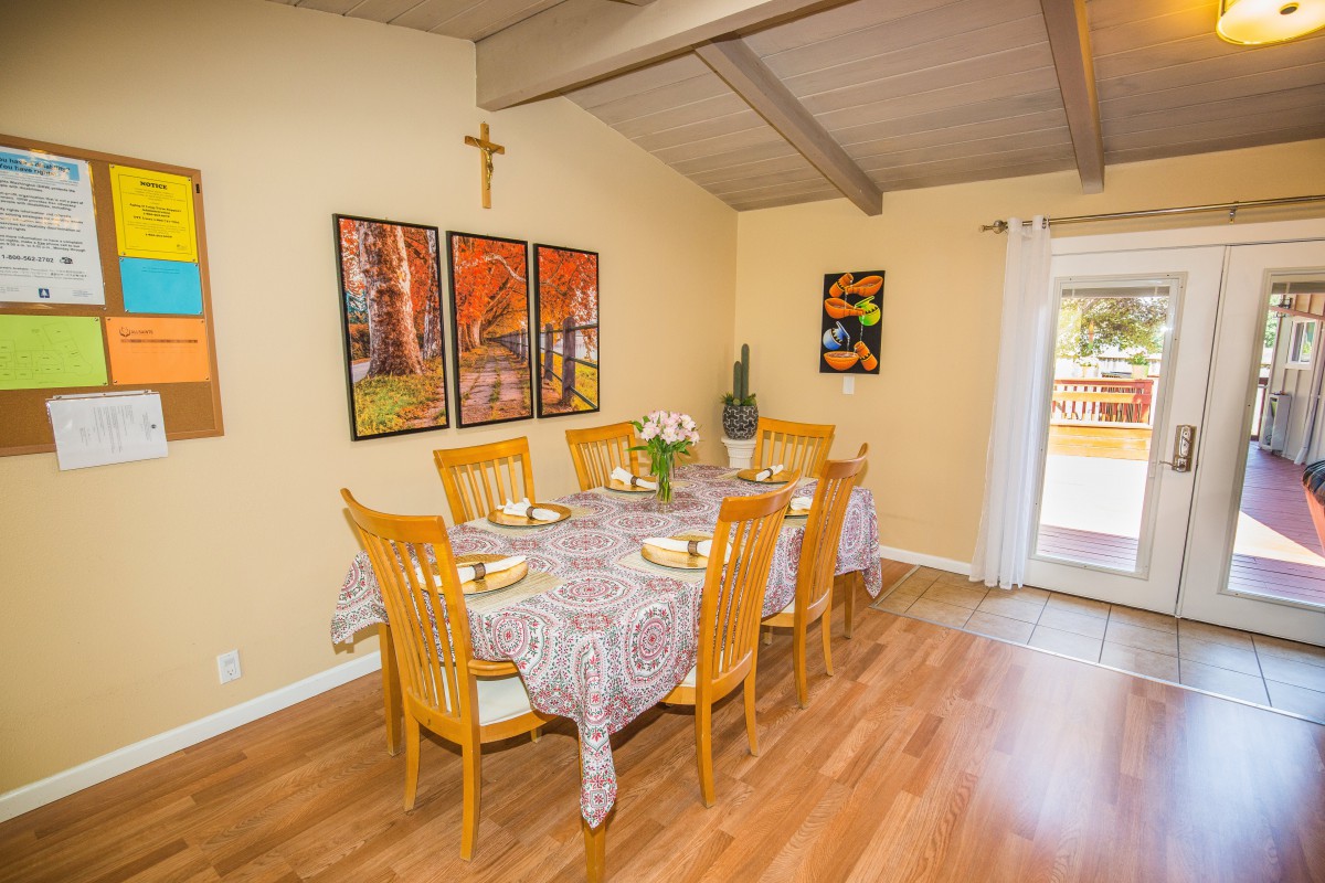 A cozy dining room with a set table and colorful artwork on the walls.