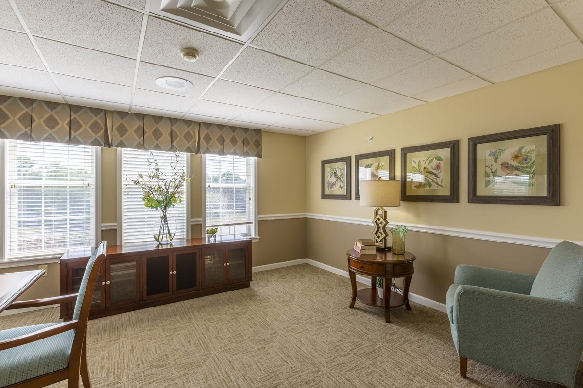 A cozy living room with elegant decor, featuring large windows, artwork on the walls, and comfortable furniture.