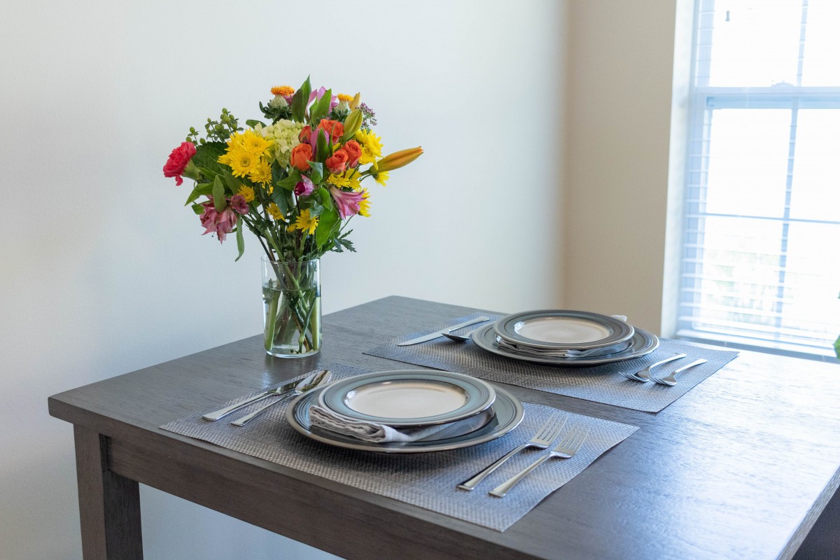 A neatly set dining table with a colorful bouquet of flowers in a vase.