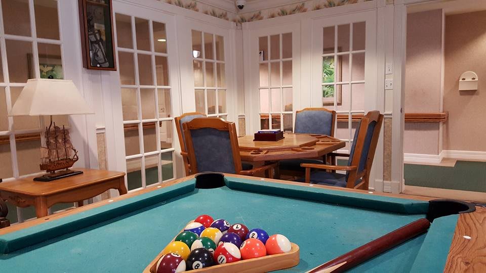 A cozy game room featuring a pool table and wooden furniture.
