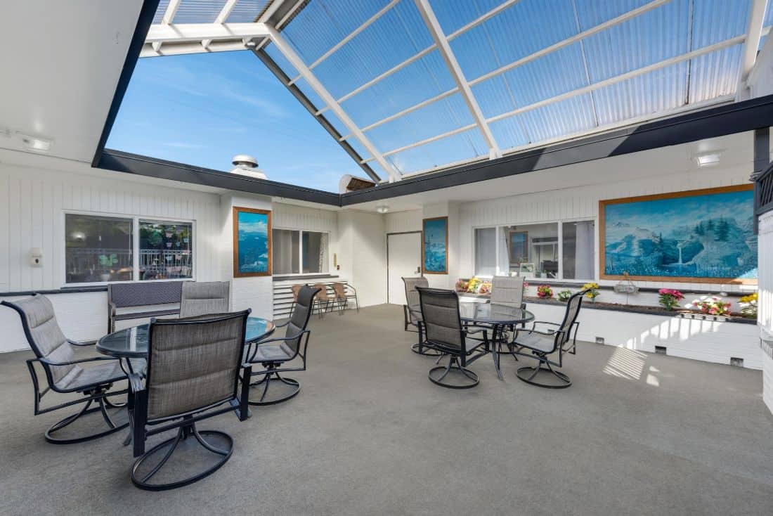 A bright patio area with tables and chairs under a glass ceiling.