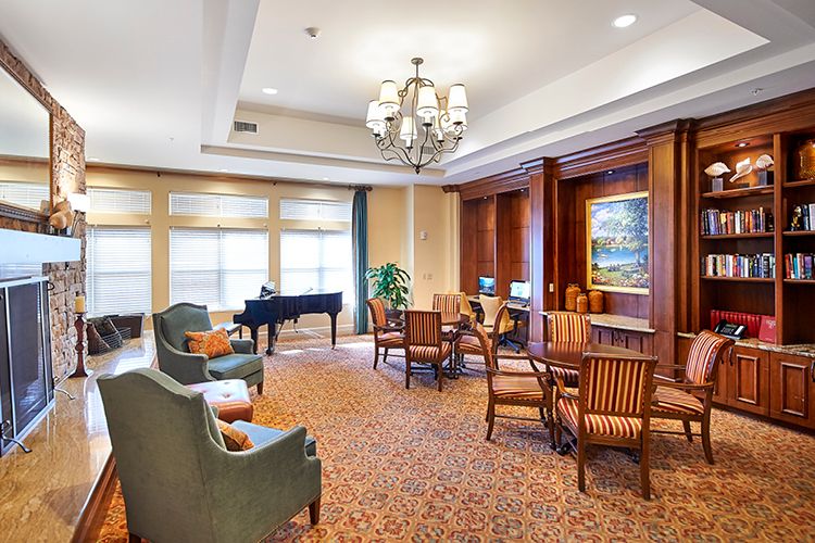 A cozy living room with a piano, elegant seating, and computer desks.