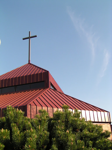 A church building with a distinctive red roof and a prominent cross.