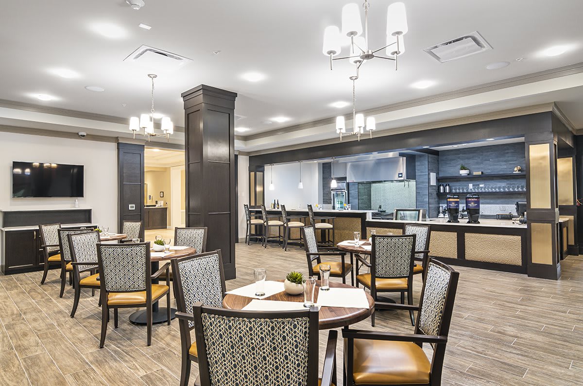 A stylish restaurant interior with neatly arranged tables and chairs, featuring modern lighting fixtures.
