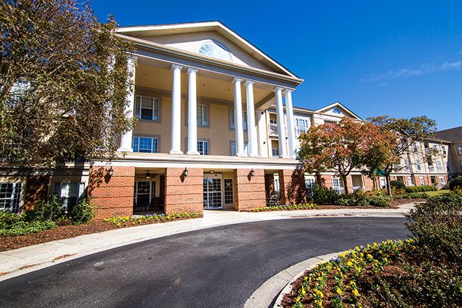 A residential building with classical columns and landscaped surroundings.