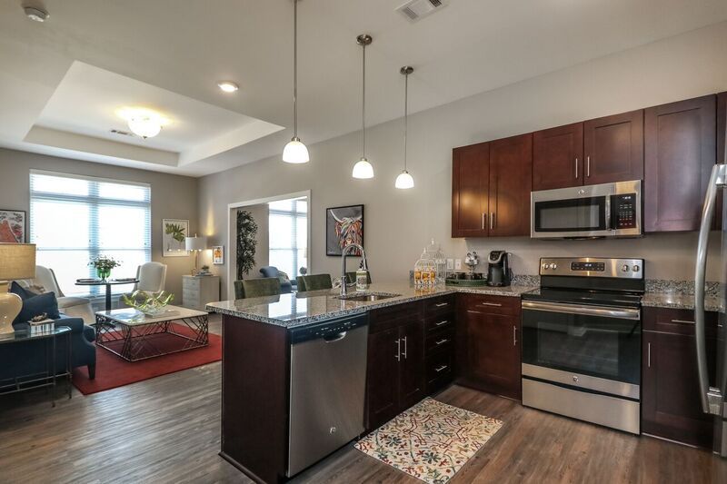 A modern kitchen with a central island, stainless steel appliances, and pendant lighting in an open floor plan setting.