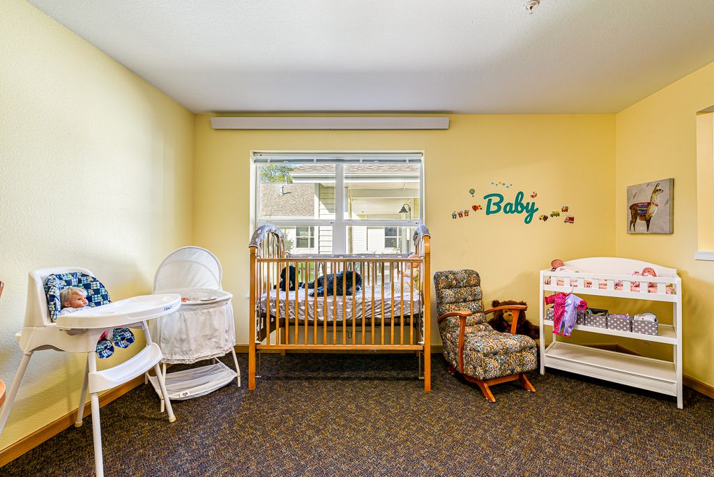 A cozy nursery with a crib, bassinet, rocking chair, and changing table.