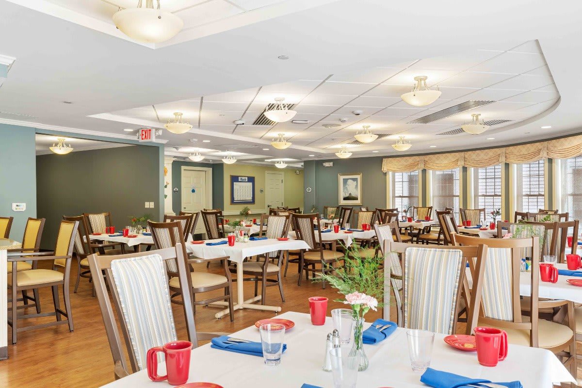 A brightly lit dining room with neatly arranged tables and chairs, ready for guests.