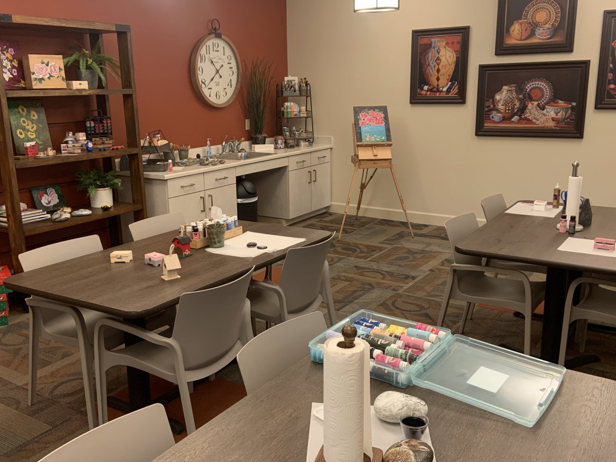 A well-equipped art room with tables, chairs, and painting supplies ready for a creative session.