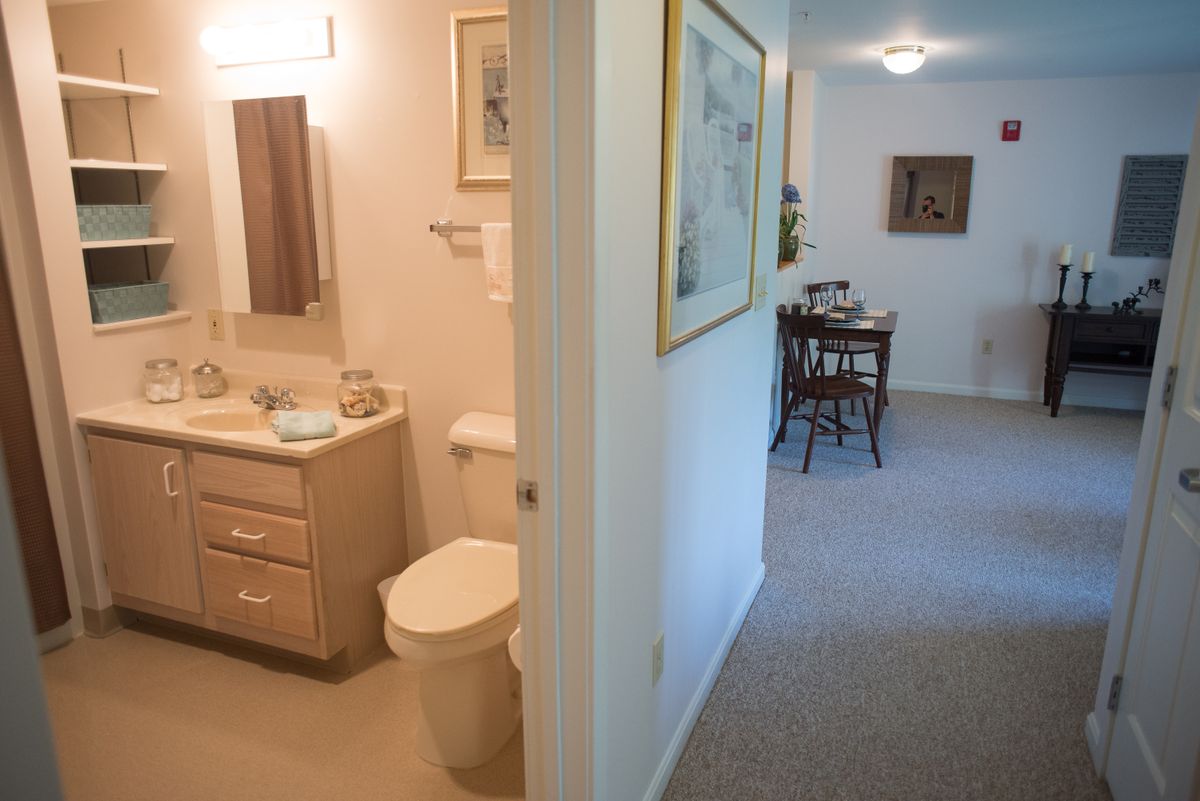 A view of a bathroom and adjoining hallway leading to a dining area.