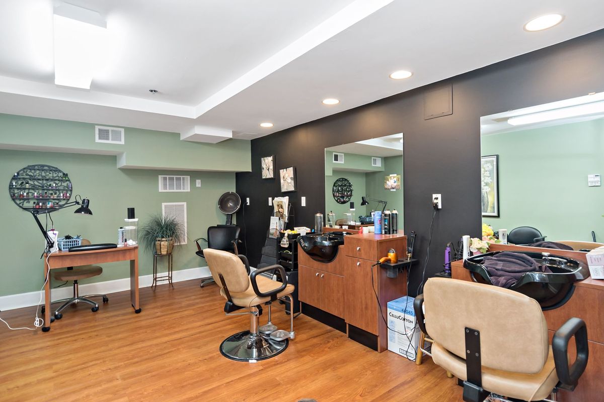 A modern hair salon interior featuring styling chairs, large mirrors, and wooden flooring.