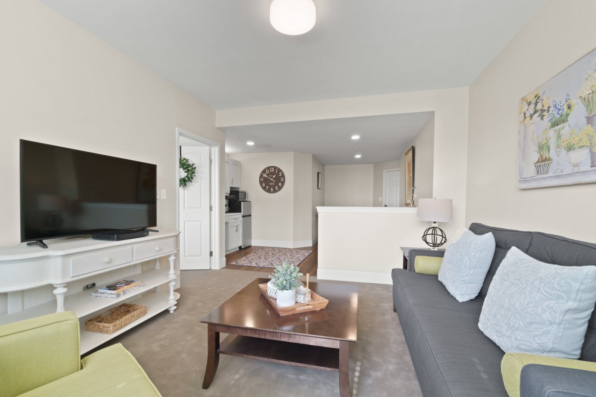 A modern living room with a comfortable sofa, wooden coffee table, and a television on a stand.