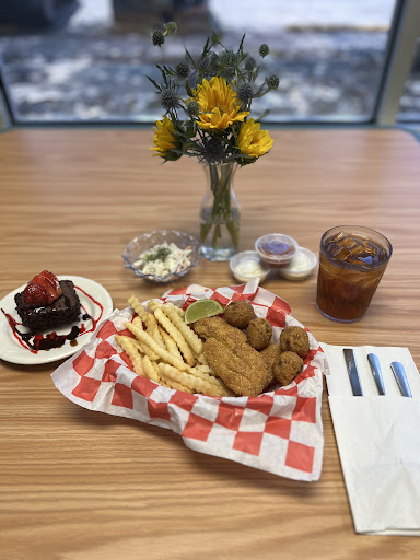 A delicious meal featuring fried chicken and fries, accompanied by a chocolate dessert and fresh flowers.