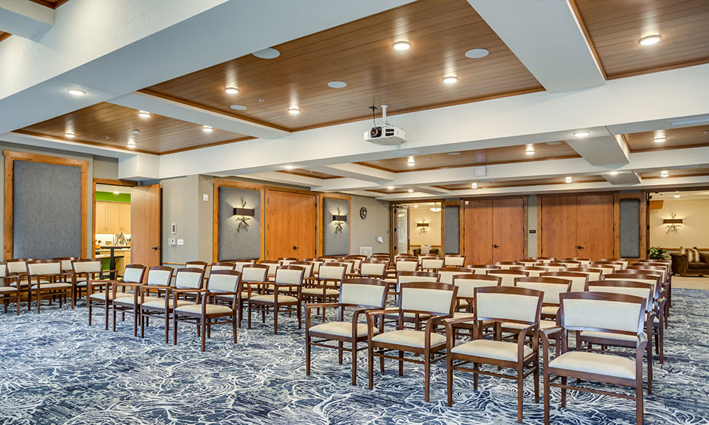 A spacious conference room with rows of chairs, a projector, and modern lighting.