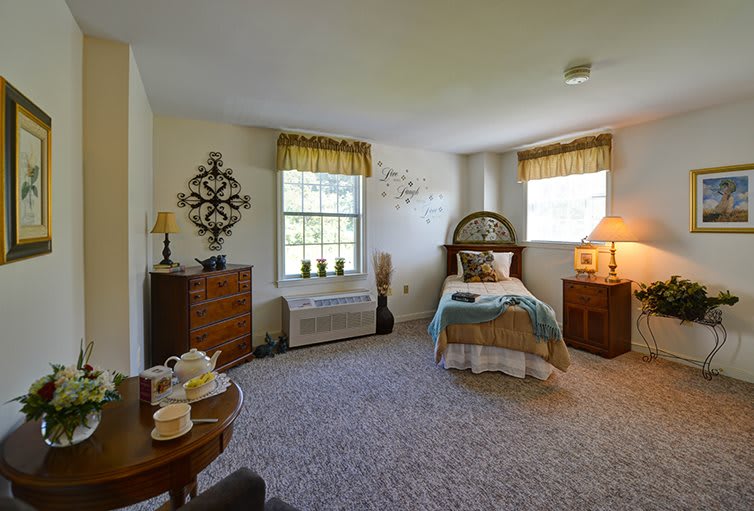 A cozy bedroom with a single bed, two windows, and warm lighting.