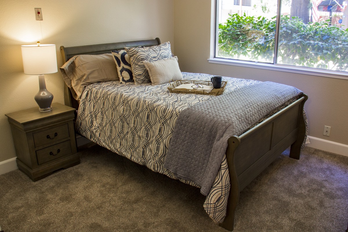 A cozy bedroom with a neatly made bed and natural light coming in through the window.