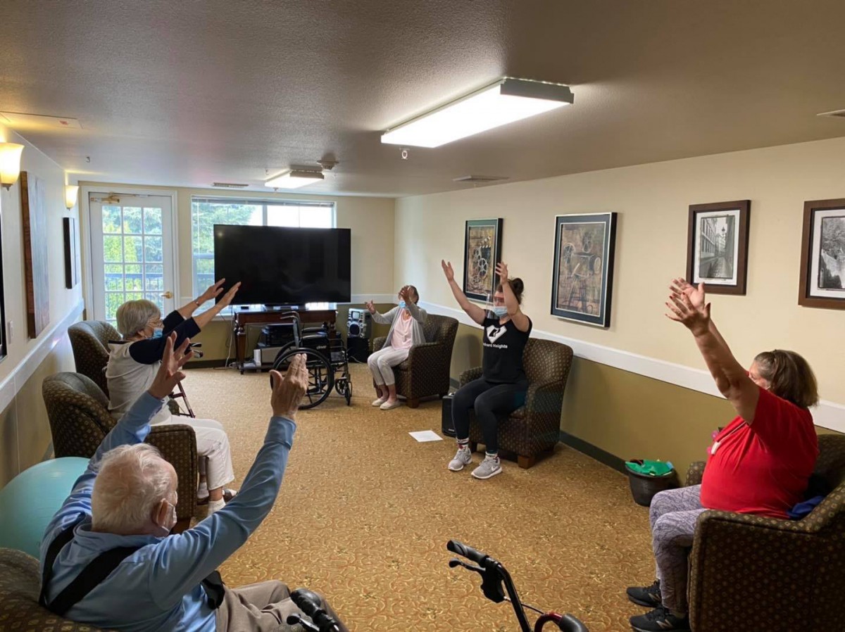 A group of elderly individuals participating in an indoor exercise session.
