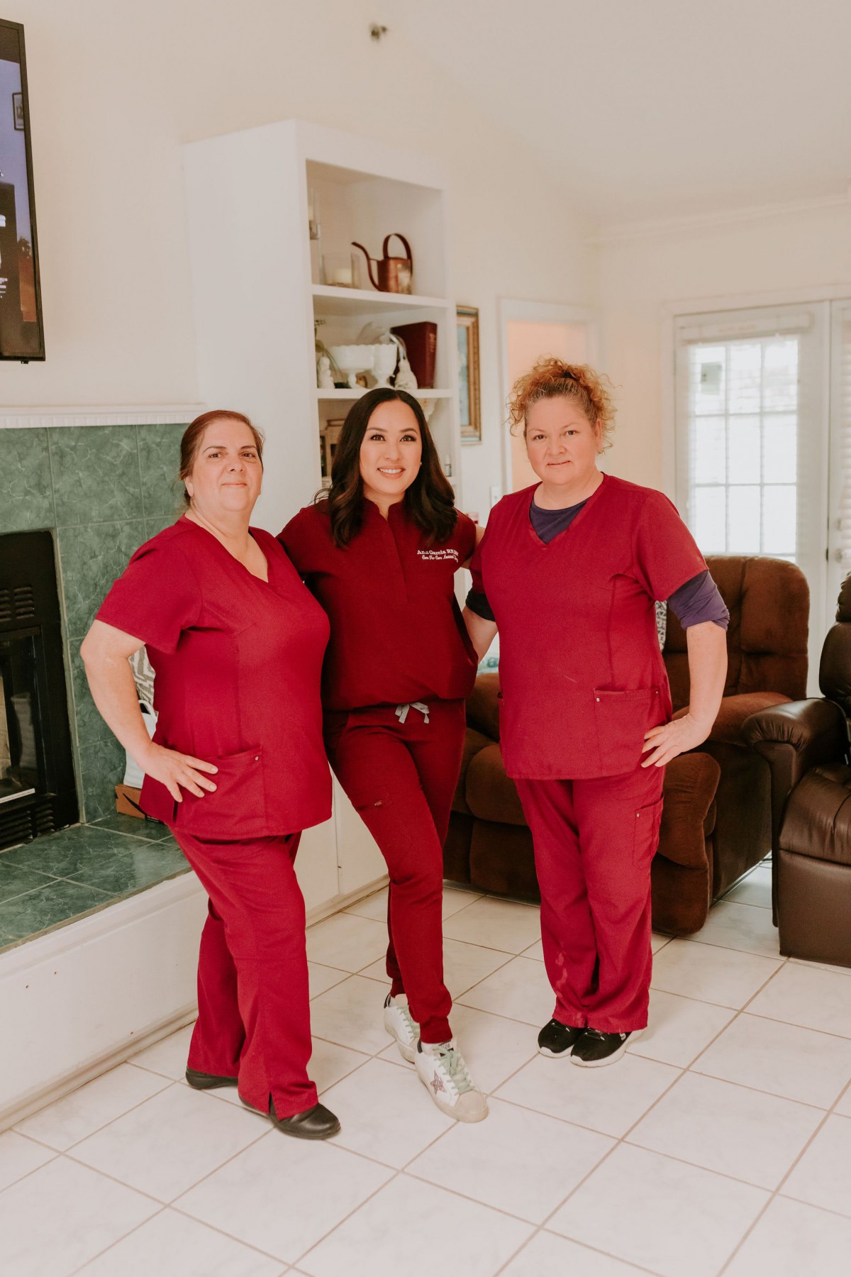Three healthcare workers in red uniforms pose for a group photo indoors.