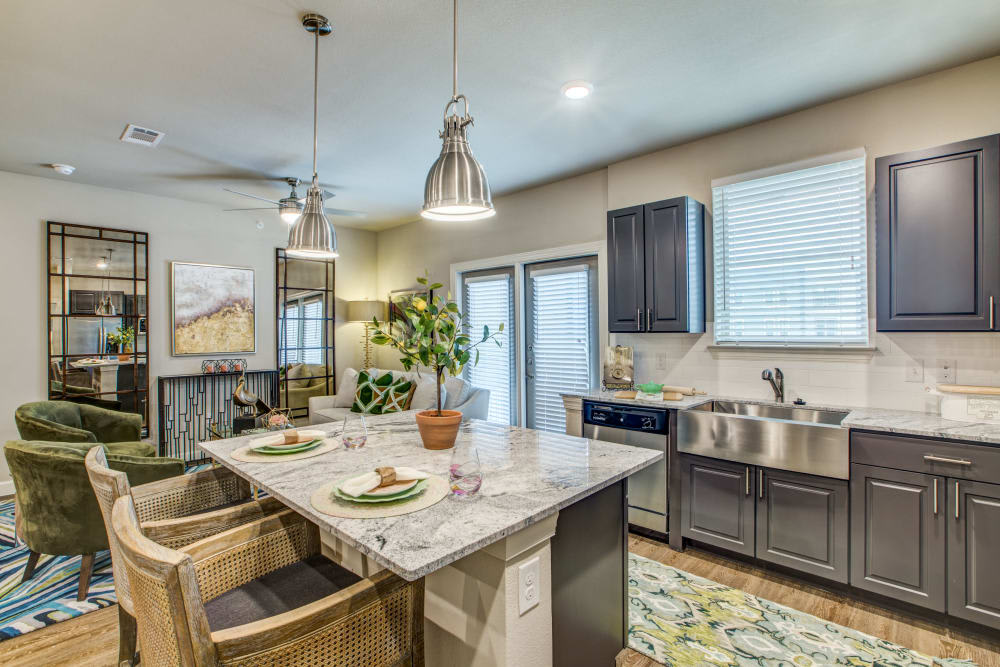 A modern kitchen with an island counter and pendant lighting, featuring stainless steel appliances and an open layout.