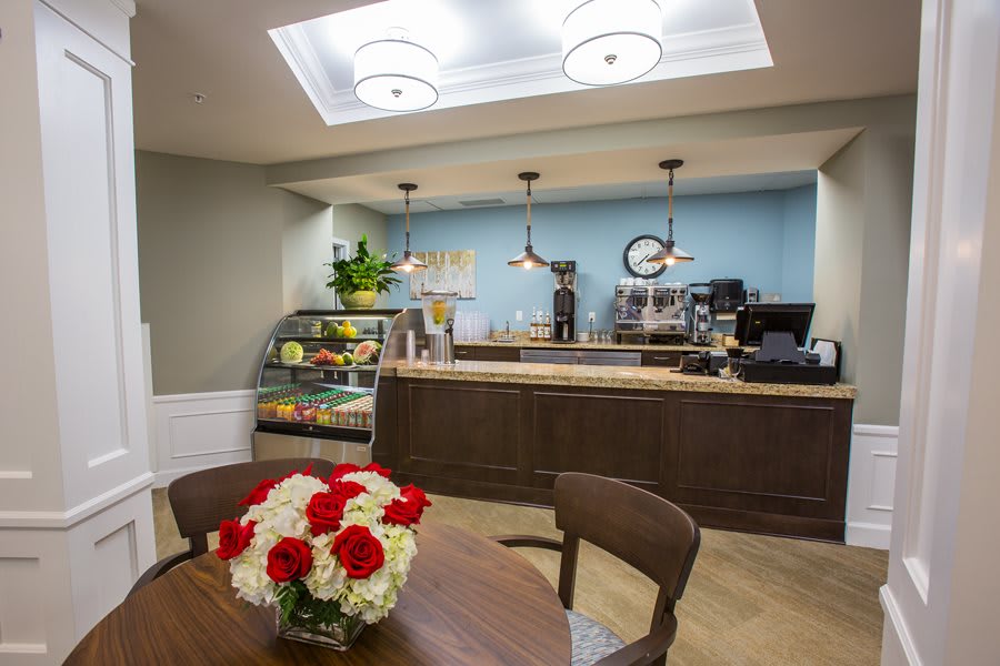 A cozy cafe interior with a flower-adorned table and a coffee counter in the background.