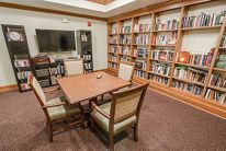 A cozy library corner with bookshelves, a table, and chairs for reading.