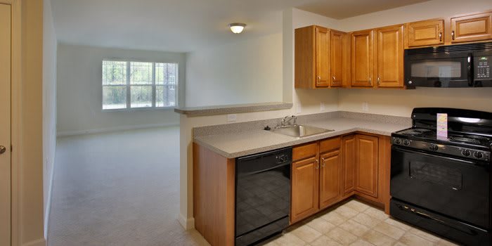Modern kitchen with wooden cabinets and a view of the living area.
