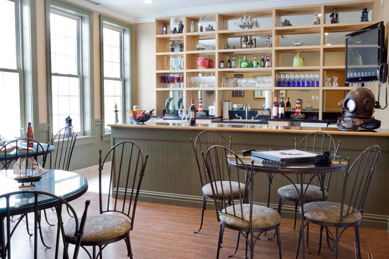 A cozy cafe interior with metal chairs, round tables, and a well-stocked bar.