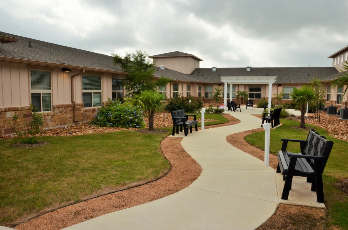 A well-maintained garden area with a winding pathway and benches outside a building.