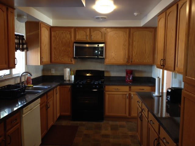 A kitchen featuring wooden cabinets and black appliances.