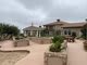 A view of a large building with a patio and landscaped area on a cloudy day.