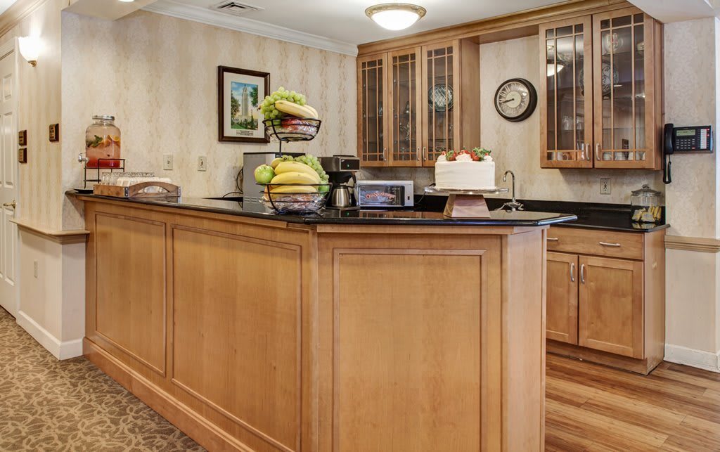 A kitchen counter with a fruit basket and wooden cabinetry.