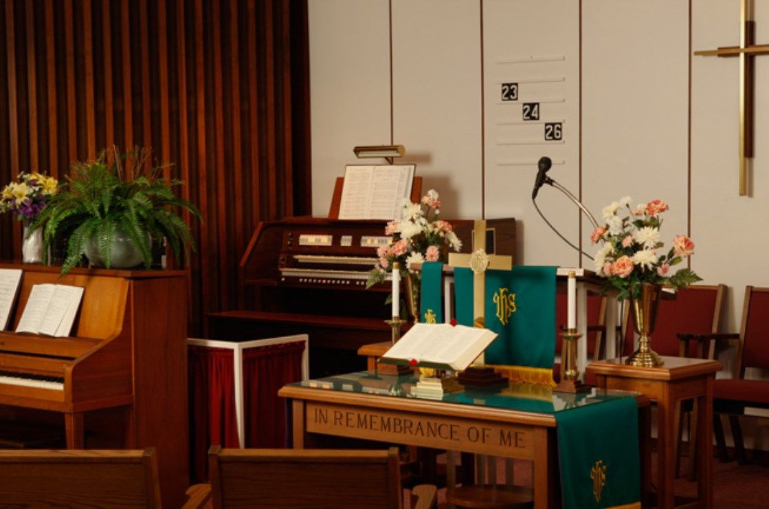 A church altar setup with an organ in the background and a microphone, adorned with flowers.