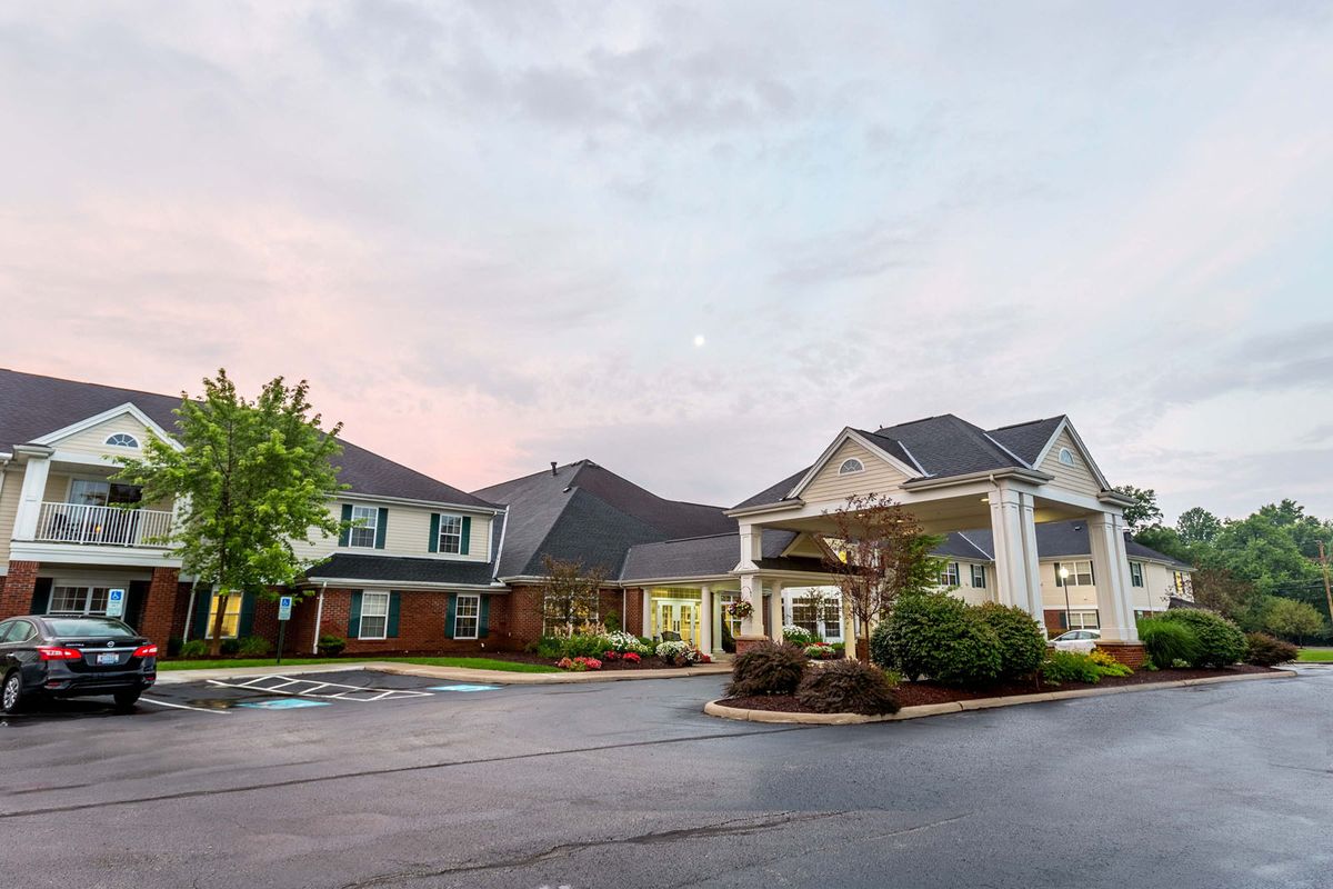 A suburban residential building with a driveway under a sunset sky.