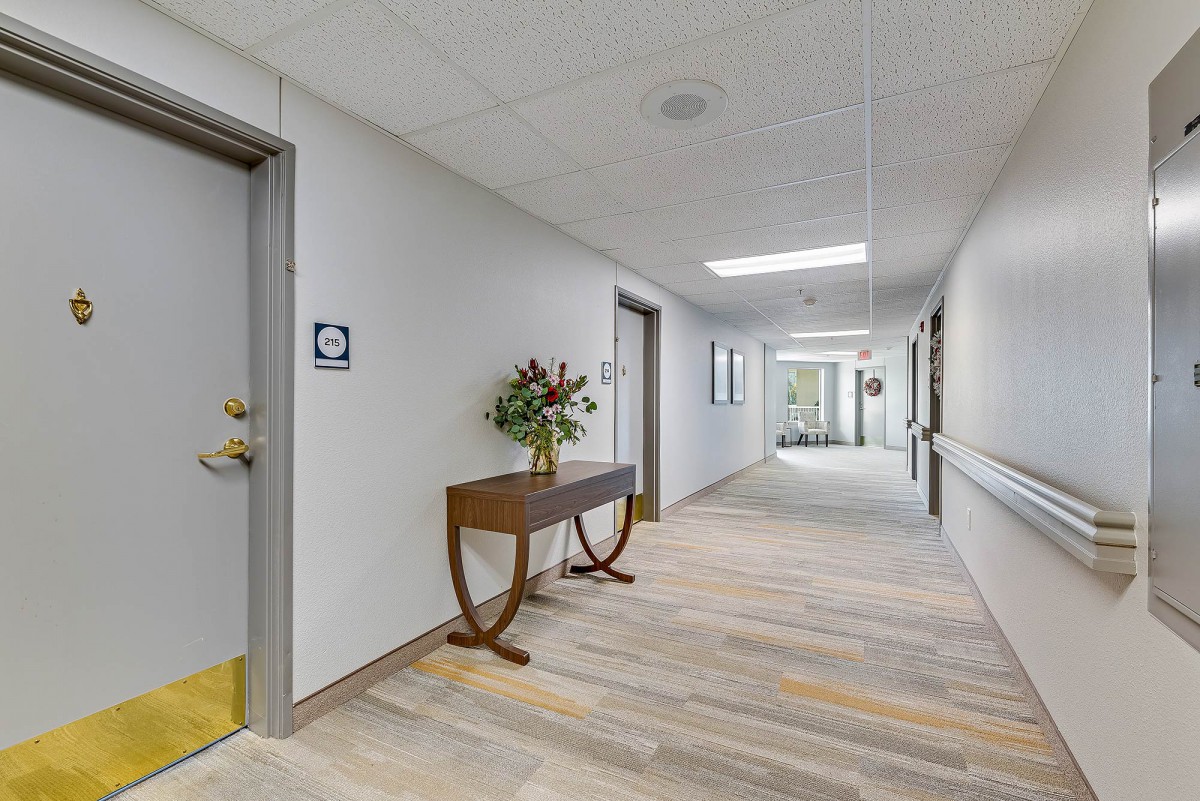 A modern hallway with a decorative table and flowers, featuring bright lighting and contemporary design.