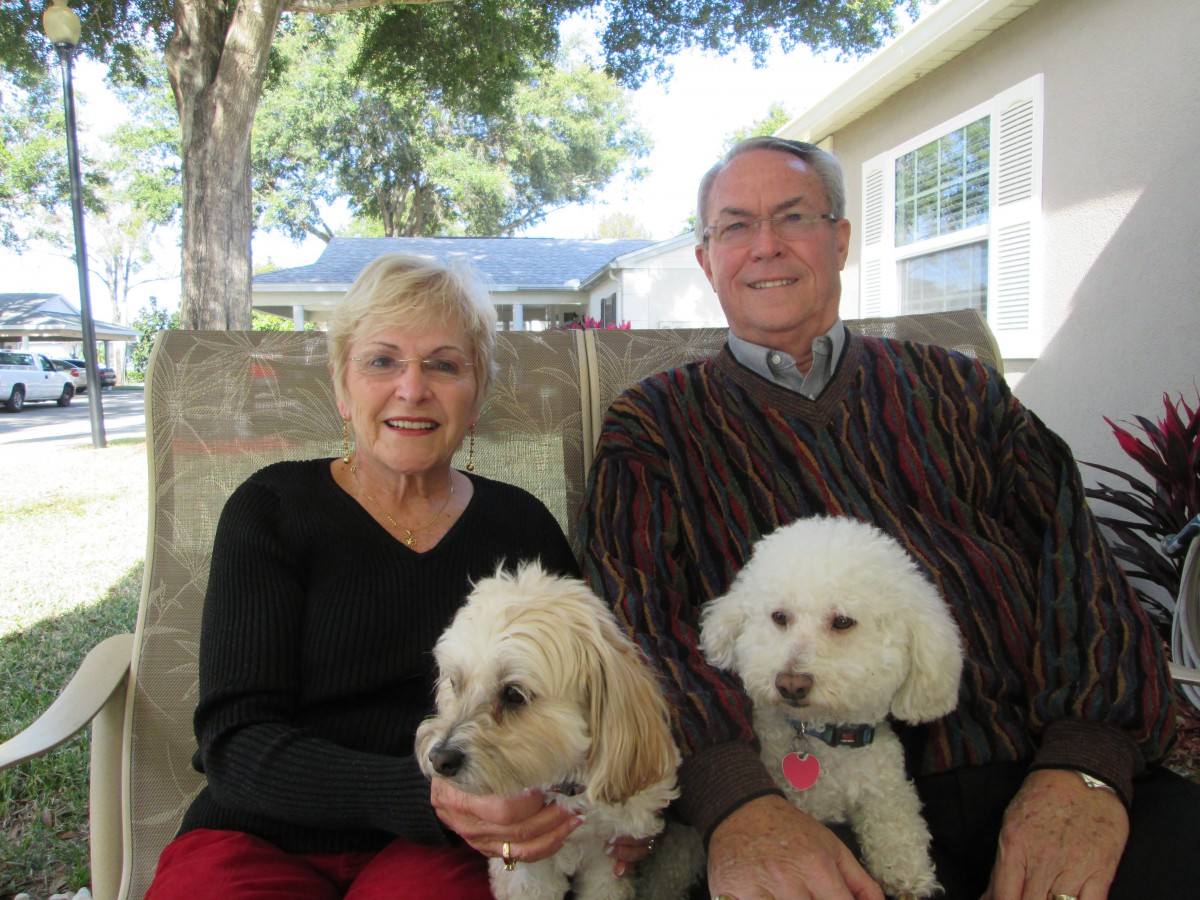 A couple sitting outside with their two dogs on a sunny day.