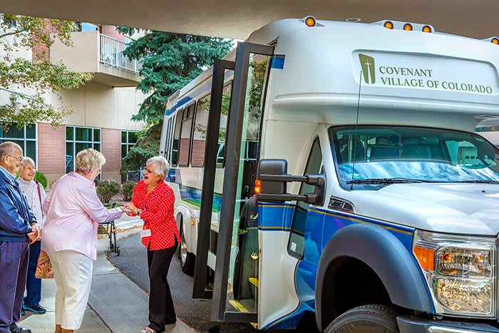 Two people interacting near a community shuttle bus.