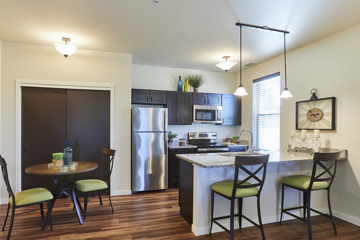 A modern kitchen interior with stainless steel appliances and a cozy dining area.