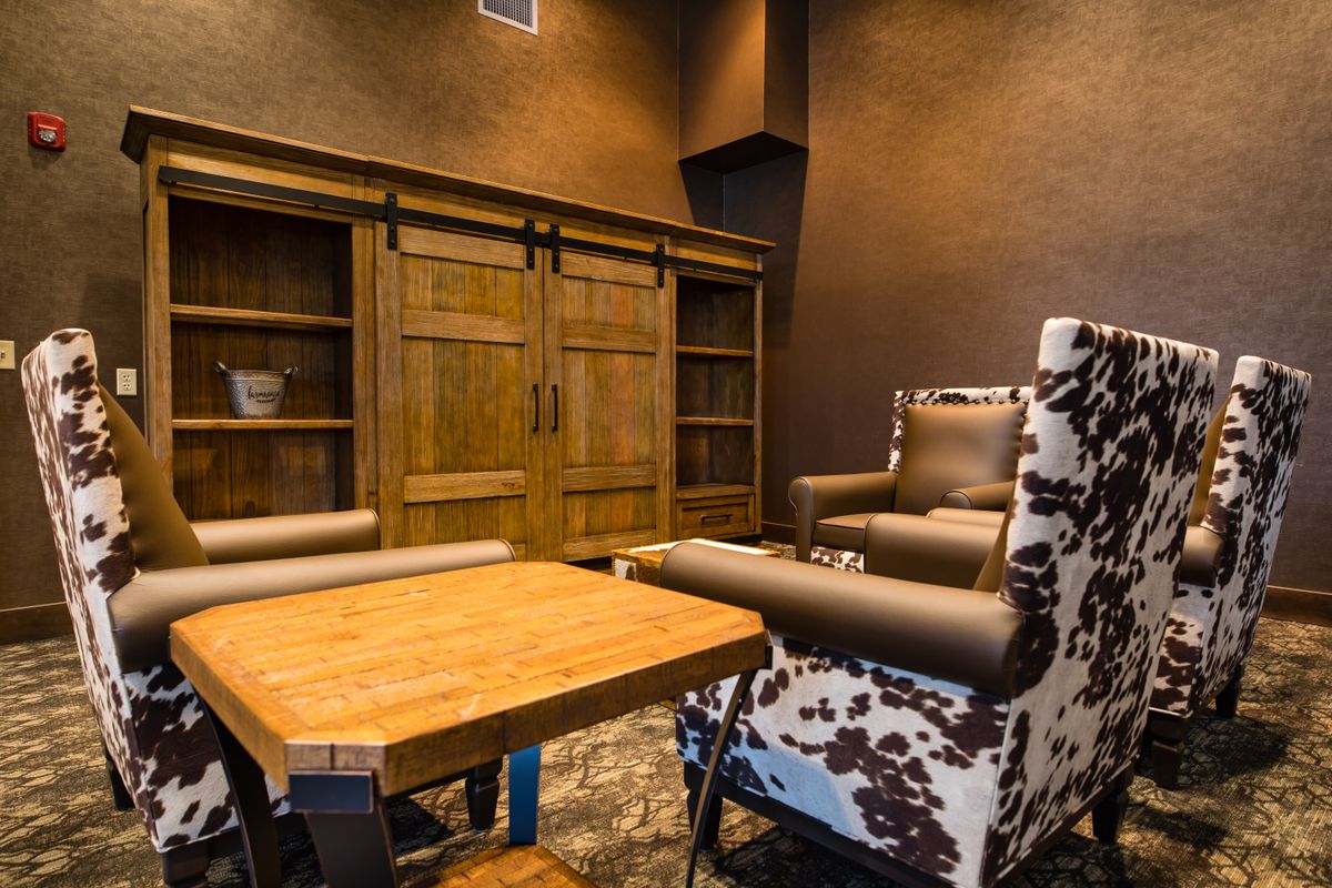 A cozy rustic interior featuring a wooden cabinet, armchairs, and a coffee table.