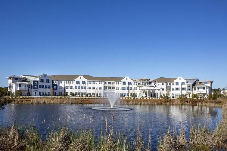 A picturesque view of a large white building with a fountain in the foreground, set against a clear blue sky.