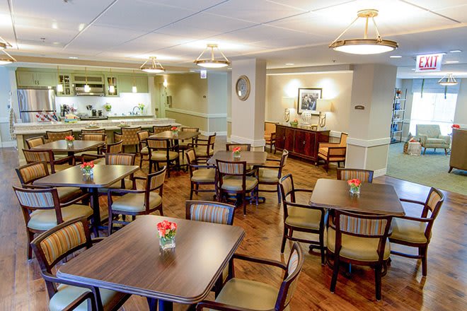 A cozy dining area with neatly arranged tables and chairs, featuring warm lighting and a welcoming atmosphere.