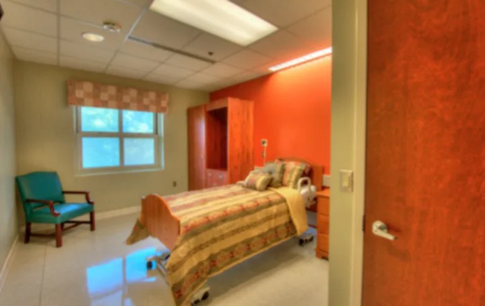 A cozy hospital room with a single bed and warm lighting.