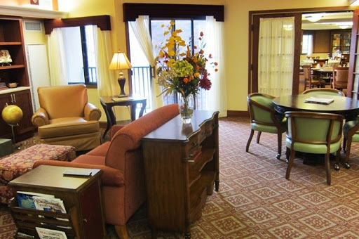 A cozy living room featuring elegant furniture and decorative flowers, illuminated by natural light.