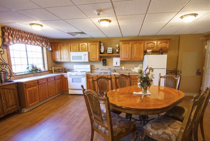 A cozy kitchen with wooden cabinets, a round dining table, and essential appliances.