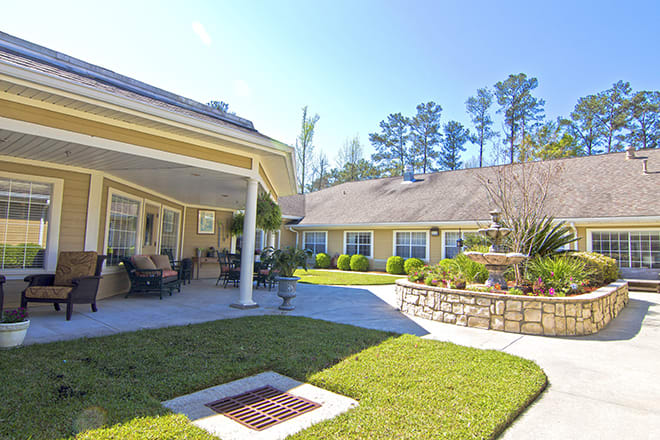 A sunny residential courtyard featuring well-maintained landscaping and a patio area.