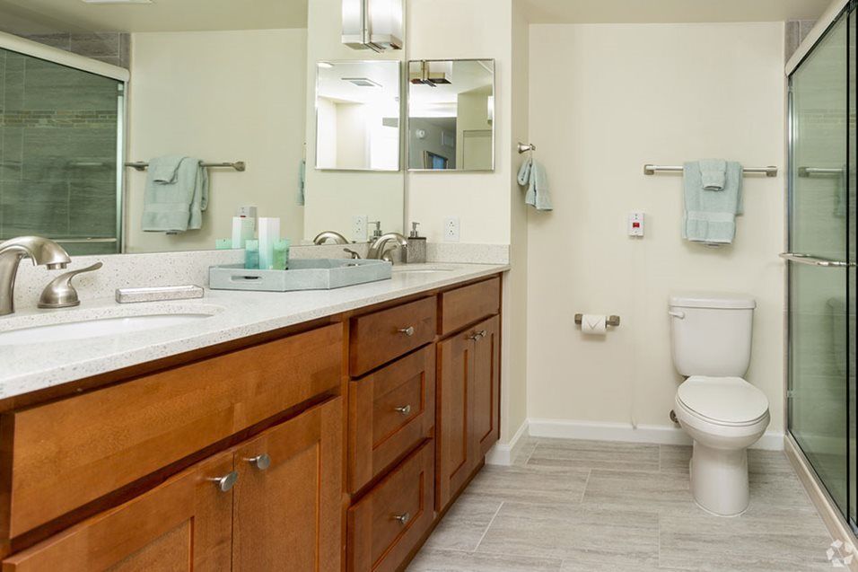 A clean and modern bathroom with a wooden vanity, large mirror, and neatly arranged towels.