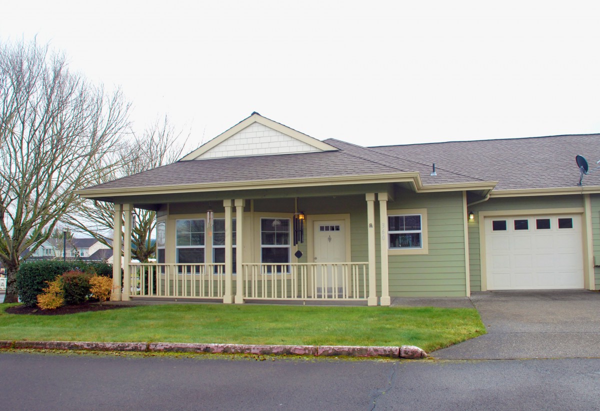 A suburban house with a front porch and well-maintained lawn.