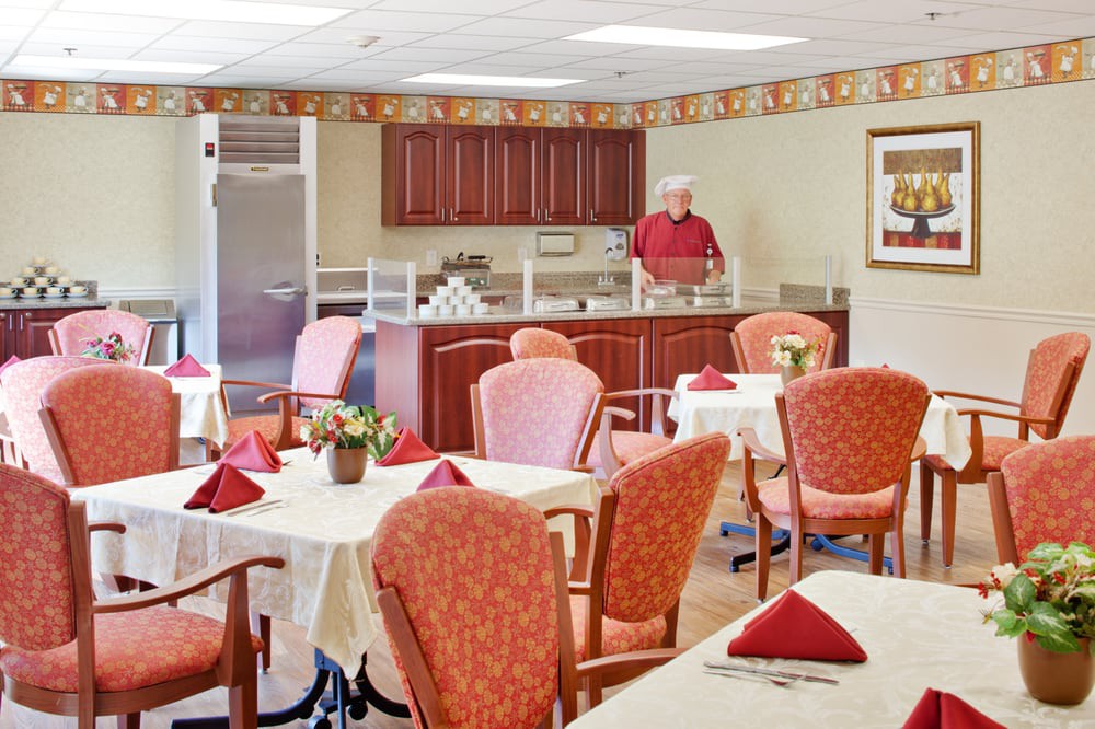 A well-organized dining area with tables set for a meal and a person standing near the counter.