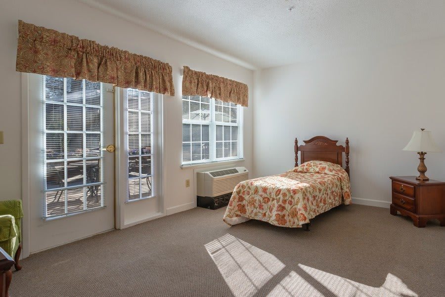 A bright bedroom with a single bed and large windows.