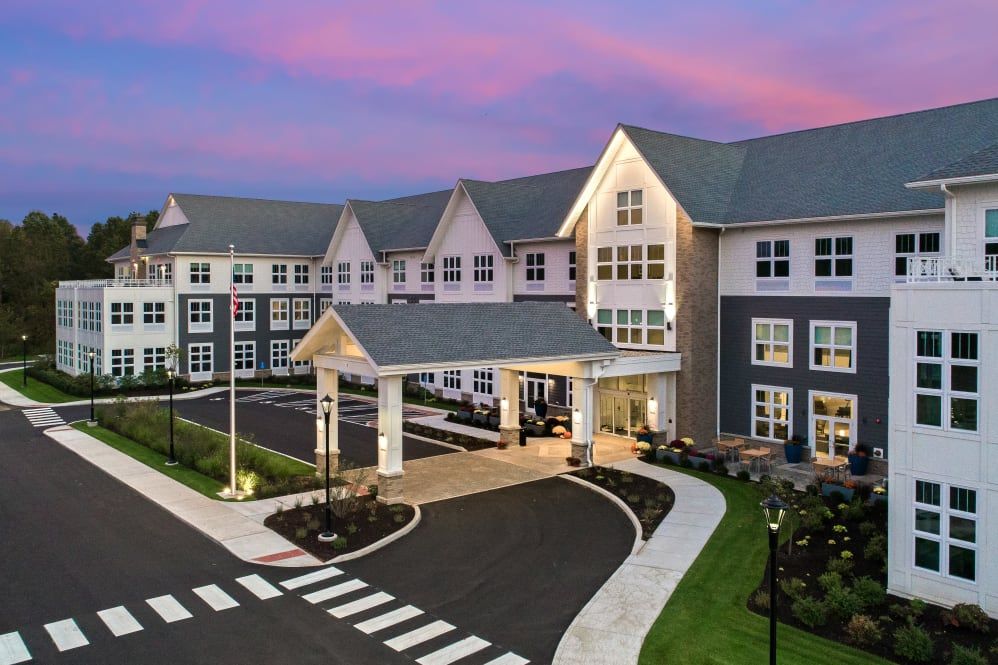 A modern residential building with a welcoming entrance under a vibrant sunset sky.
