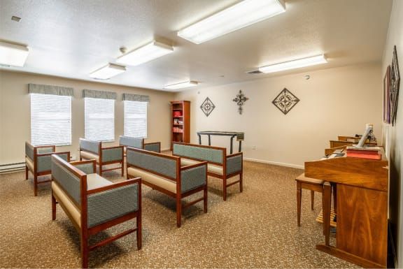 A small chapel interior featuring rows of pews and religious decorations on the walls.